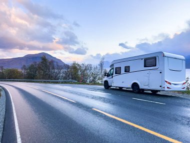 A motorhome parked by the road in the autumn landscape of the Lyngen Alps, Norway, with mountains. clipart