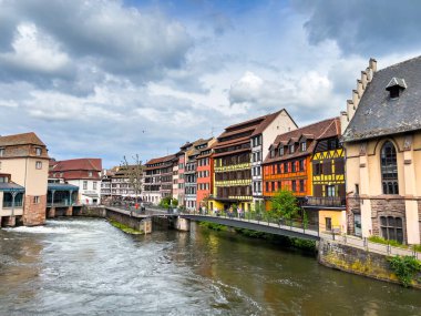 Strasbourg, Fransa; 7 Mayıs 2024: Strasbourg, Fransa 'da bahar mevsimi, parlak bir gökyüzüne sahip güzel bir nehir boyunca yarım ahşap binalar sergiliyor. 4K UHD