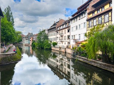 Strasbourg, Fransa; 7 Mayıs 2024: Strasbourg, Fransa 'da bahar mevsimi, parlak bir gökyüzüne sahip güzel bir nehir boyunca yarım ahşap binalar sergiliyor. 4K UHD