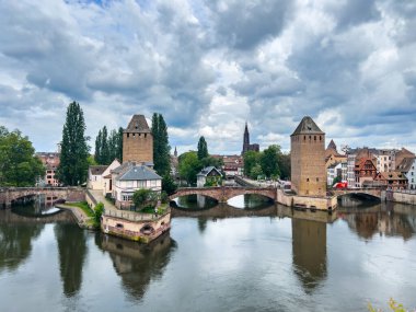 Strasbourg, Fransa; 7 Mayıs 2024: Strasbourg, Fransa 'da bahar mevsimi, parlak bir gökyüzüne sahip güzel bir nehir boyunca yarım ahşap binalar sergiliyor. 4K UHD