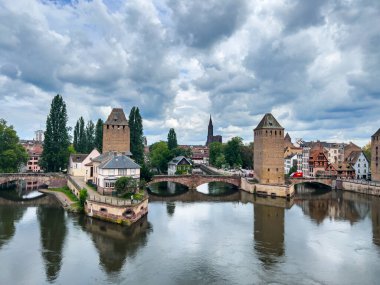 Strasbourg, Fransa; 7 Mayıs 2024: Strasbourg, Fransa 'da bahar mevsimi, parlak bir gökyüzüne sahip güzel bir nehir boyunca yarım ahşap binalar sergiliyor. 4K UHD