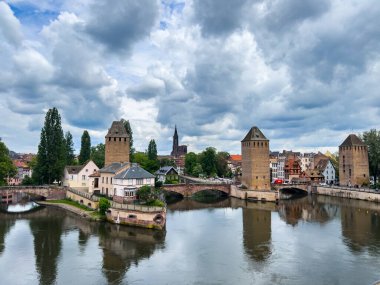 Strasbourg, Fransa; 7 Mayıs 2024: Strasbourg, Fransa 'da bahar mevsimi, parlak bir gökyüzüne sahip güzel bir nehir boyunca yarım ahşap binalar sergiliyor. 4K UHD