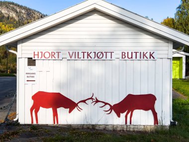 Vestsida, Norveç; 29 Eylül 2024: Norveç 'in vahşi oyun dükkanı, üzerinde savaşan iki kırmızı geyik silueti bulunan beyaz ahşap bir dış görünüme sahip.
