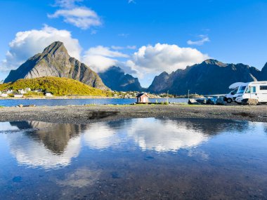 Reine, Norveç; 12 Eylül 2024: Norveç 'teki Lofoten Adaları' nda deniz kenarında park etmiş kampçılar, arka planda dağlarla birlikte su birikintisine yansıyor.