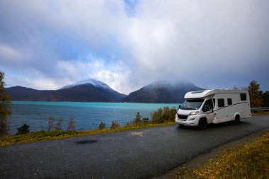 A motorhome parked by the road in the autumn landscape of the Lyngen Alps, Norway, with mountains. clipart