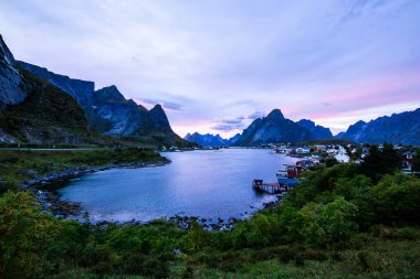 Autumn sunset in Reine, Lofoten Islands, northern Norway, with dramatic mountains, calm waters, and traditional houses along the shore. clipart