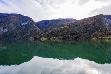 Autumn landscape in Lustrafjorden, Norway, featuring clear water reflections, mountains, and colorful foliage. clipart