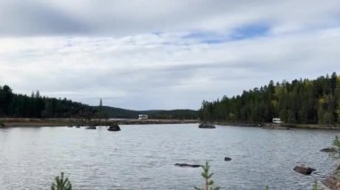 Beyaz karavan Finlandiya 'da ormanla çevrili bir göl kenarında park halindedir.