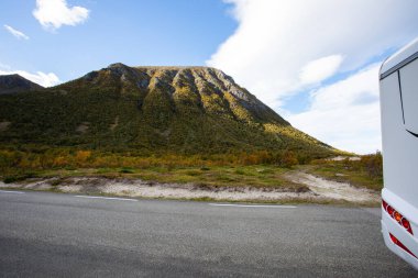 Yağmurlu bir sonbahar gününde Norveç, Bodalen 'de manzaralı bir dağ manzaralı yol kenarına park edilmiş beyaz bir karavan.