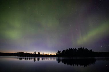 İsveç 'in Kiruna kentindeki kuzey ışıkları Eylül ayında sakin suları yıldızlar ve ormanlarla yansıtıyor..
