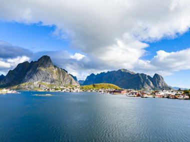 Norveç 'in Hamnoy, Lofoten Adaları' nda gün doğumu, kıyı şeridi boyunca geleneksel kırmızı evler ve dramatik dağlar..
