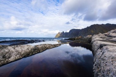 Autumn landscape of Senja Island in Norway with colorful foliage, mountains, and a serene fjord. clipart