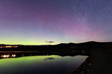 The Northern Lights and Milky Way above the mountains near Dovrefjell National Park, Norway. clipart