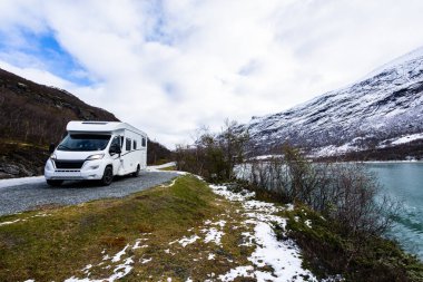 Norveç 'in güneyindeki Sognefjellsvegen yolunda karla kaplı dağlar ve manzaralı manzaralarla çevrili bir karavan..