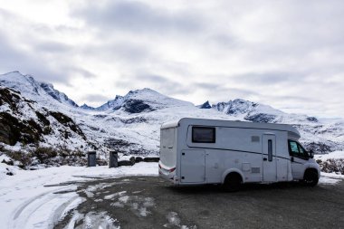 Norveç 'in güneyindeki Sognefjellsvegen yolunda karla kaplı dağlar ve manzaralı manzaralarla çevrili bir karavan..