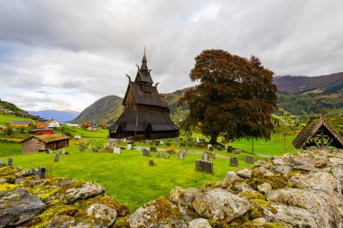 Norveç 'teki Hopperstad Stavkyrkje, güz ağaçları ve huzurlu bir mezarlıkla çevrili tarihi bir ahşap kilise..