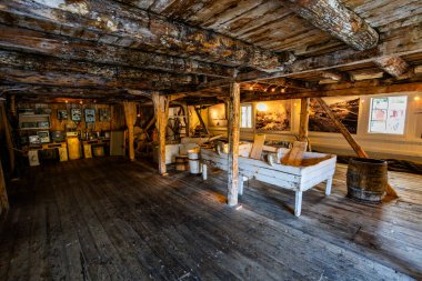 Norveç, Lofoten Adaları 'ndaki Nusfjord manzaralı, kırmızı ve sarı ahşap evler, tekneler ve kristal berrak sularla.