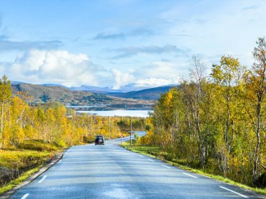 Norveç, Senja Adası 'nın sonbahar manzarası. Renkli ağaçlar, dingin su yansımaları ve dramatik dağlar..