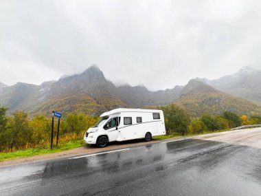 Yağmurlu bir sonbahar gününde Norveç, Bodalen 'de manzaralı bir dağ manzaralı yol kenarına park edilmiş beyaz bir karavan.