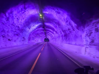 Illuminated purple road passing through laerdal tunnel in norway clipart