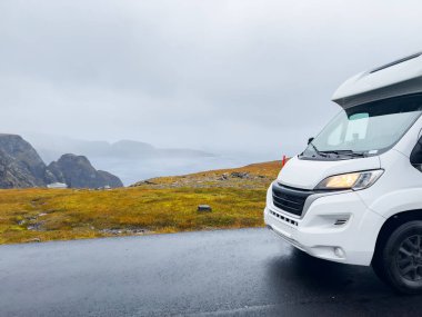 White camper van driving on e69 road to nordkapp, norway, in a rainy and foggy day clipart