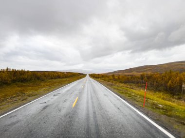 Norveç 'te bulutlu bir gökyüzünün altında nefes kesen manzaralı bir yol. Nordkapp