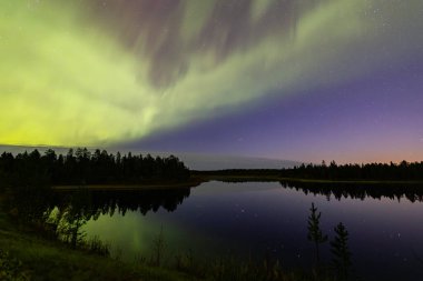 İsveç 'in Kiruna kentindeki kuzey ışıkları Eylül ayında sakin suları yıldızlar ve ormanlarla yansıtıyor..