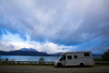 A motorhome parked by the road in the autumn landscape of the Lyngen Alps, Norway, with mountains. clipart