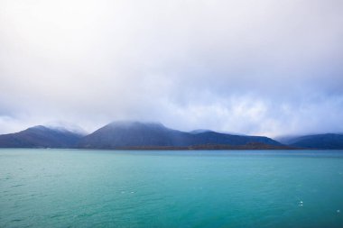 Norveç 'teki Lyngen Alpleri' nin sonbahar manzarası. Karlı zirveleri, dramatik bulutları ve sakin fiyortları var..
