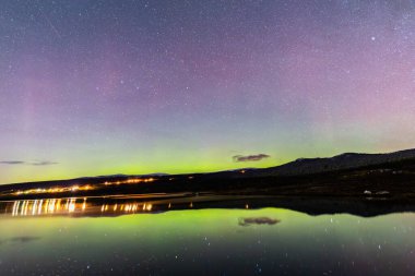 The Northern Lights and Milky Way above the mountains near Dovrefjell National Park, Norway. clipart