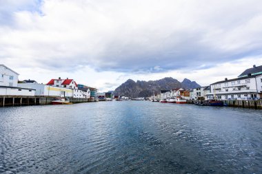Norveç, Lofoten Adaları 'ndaki Henningsvaer manzarası liman boyunca uzanan ve arka planda dağlar bulunan geleneksel binaları gösteriyor..
