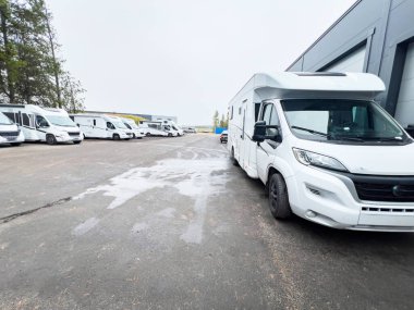 Bir araba galerisinin ya da kiralama şirketinin otoparkına park etmiş beyaz karavan minibüsleri müşterilerin gelip onları almaları için hazır bekliyor.