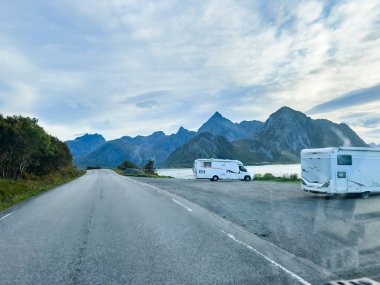 Motorhomes at sunrise with the stunning reflection of mountains and scenic landscape in Reine, Lofoten Islands, northern Norway. clipart