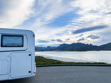 Motorhomes at sunrise with the stunning reflection of mountains and scenic landscape in Reine, Lofoten Islands, northern Norway. clipart