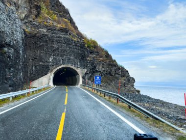 Güzel bir sonbahar manzarası: sonbahar yapraklarıyla dağlık bir arazide kıvrılan bir göl yolu.