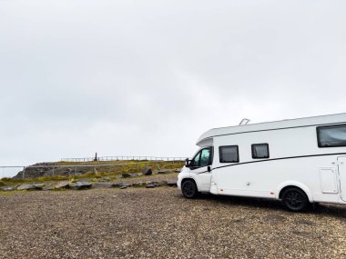 Sisli bir günde iki karavan manzaralı bir yere park edilmiş, doğanın sakinliği ve enginliğinin tadını çıkarıyorlar. Nordkapp