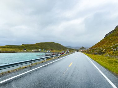 Norveç 'te bulutlu bir gökyüzünün altında nefes kesen manzaralı bir yol. Nordkapp