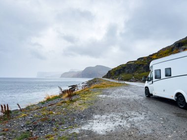Yağmurlu ve sisli bir günde Nordkapp, Norveç 'e giden e69 yolunda giden beyaz bir karavan.