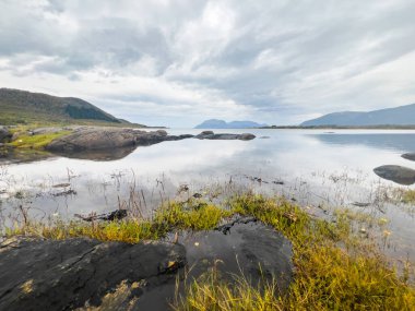 Sükunet kristal berrak su Kuzey Norveç 'te dağları yansıtıyor bulutlu bir gökyüzünün altında