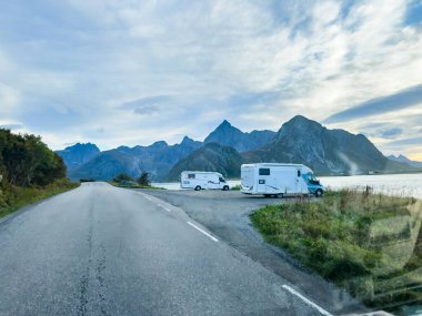 Motorhomes at sunrise with the stunning reflection of mountains and scenic landscape in Reine, Lofoten Islands, northern Norway. clipart