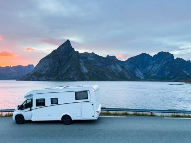Kuzey Norveç 'teki Reine, Lofoten Adaları' ndaki dağların ve manzaranın çarpıcı yansımasıyla gün doğumunda motorlu evler.