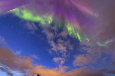 Kuzey Norveç 'in kuzeyindeki Lofoten Adaları üzerindeki göz kamaştırıcı Kuzey Işıkları, dağların üzerindeki gece gökyüzünü aydınlatan canlı renklerle.