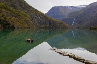 Autumn landscape in Skjolden, Norway, with a calm lake reflecting the mountains and colorful foliage. clipart