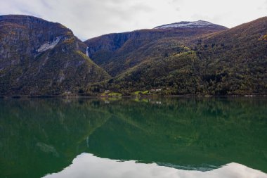 Autumn landscape in Lustrafjorden, Norway, featuring clear water reflections, mountains, and colorful foliage. clipart