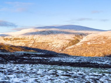 Autumn landscape in Dovrefjell National Park, south Norway, surrounded by snow and vegetation clipart