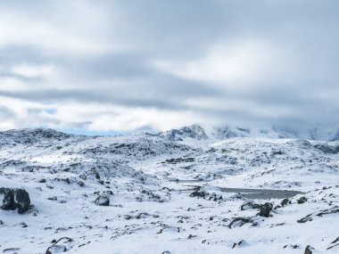 A winter landscape along the Sognefjellsvegen road in south Norway, featuring snow-covered mountains and a vast, serene terrain. clipart