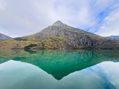 Autumn landscape in Skjolden, Norway, with a calm lake reflecting the mountains and colorful foliage. clipart