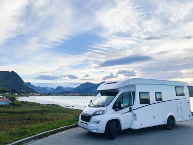 Kuzey Norveç 'teki Reine, Lofoten Adaları' ndaki dağların ve manzaranın çarpıcı yansımasıyla gün doğumunda motorlu evler.
