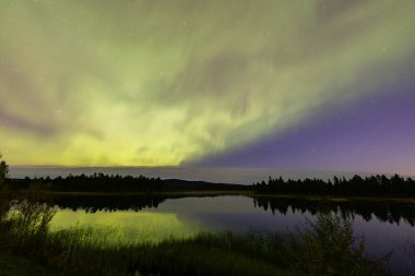 İsveç 'in Kiruna kentindeki kuzey ışıkları Eylül ayında sakin suları yıldızlar ve ormanlarla yansıtıyor..