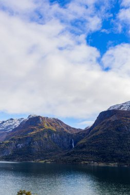 Norveç 'in Lustrafjorden kentindeki sonbahar manzarasında berrak su yansımaları, dağlar ve renkli yeşillikler yer almaktadır..